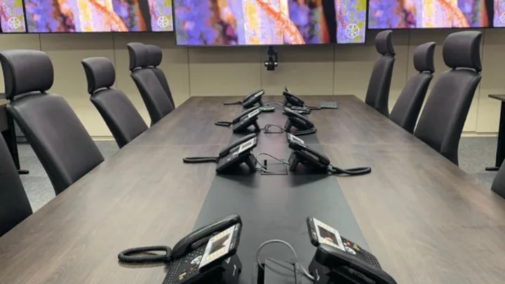 Sala de comando com mesa de crise, telefones dedicados e monitores no projeto GSI