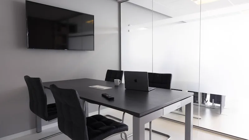 Sala de reuniao com mesa, cadeiras e televisor na parede