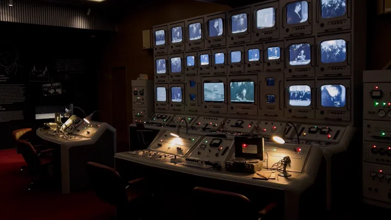 Sala de controle com múltiplos monitores e posições de operação
