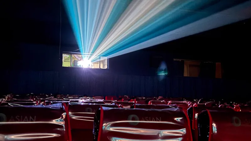 Feixes de luz de projetor iluminando auditório vazio com poltronas