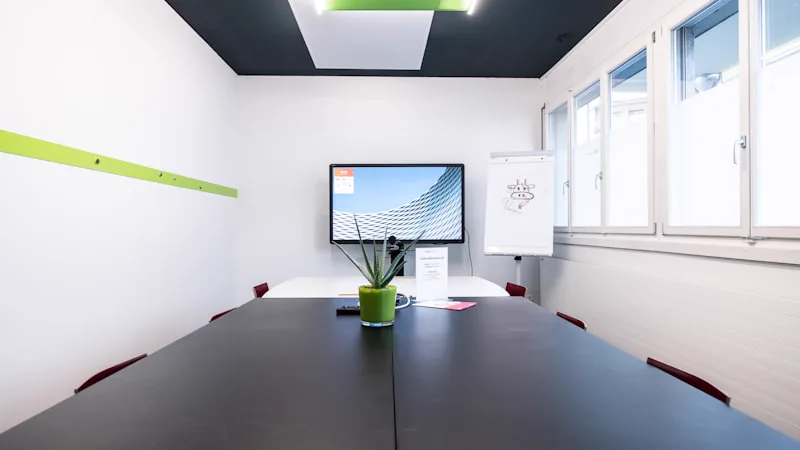 Sala com mesa de reunião e televisor de parede